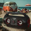 A portable speaker is placed on a wooden table on a beach, with a vintage van and people in the background. Produktbild-Vorschau