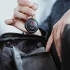 A person is holding a black key finder and placing it into a black bag. Podgląd zdjęcia produktu