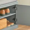 A close-up view of a gray shoe cabinet with its door open, revealing shelves with shoes and a woven basket. Náhľad obrázku produktu