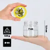 A hand holds a jar lid with a bee design above an empty glass jar, with size and weight indicators. Podgląd zdjęcia produktu