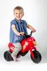 A young child is sitting on a red toy motorcycle against a white background. Anteprima dell’immagine prodotto