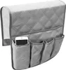 A grey quilted sofa armrest organizer with multiple pockets, one of which holds a smartphone. Produktbild-Vorschau