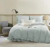 A bedroom scene with a bed made with light blue bedding, a chair, and a floor lamp. Produktbild-Vorschau