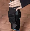 A person's hand is inserting a black rectangular device into a black fabric sleeve on a person's leg. Podgląd zdjęcia produktu