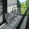 A balcony with a small table and chairs, overlooking a garden. Produktbild-Vorschau