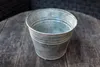 A galvanized metal pot sits on a wooden table. Produktbild-Vorschau