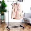 A beige jacket hangs on a black rolling garment rack in a room with a plant and a chair. Náhled obrázku produktu