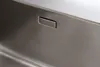 A close-up view of a stainless steel sink with a rectangular drain cover. Produktbild-Vorschau