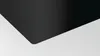 A close-up abstract view of a black glass ceramic cooktop with a white background. Podgląd zdjęcia produktu
