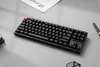 A black mechanical keyboard with a red keycap is placed on a light gray surface, with a magazine and a pen in the background. Produktbild-Vorschau