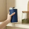 A hand holds a blue electric coffee grinder on a shelf next to a jar of mung beans. Produktbild-Vorschau