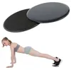 Zwei schwarze und graue Core-Slider, einer mit glatter Oberseite und einer mit strukturierter Oberseite, neben einer Frau in Plank-Position, die ähnliche Slider unter ihren Füßen verwendet Podgląd zdjęcia produktu