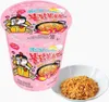 A pink cup of instant ramen with a bowl of cooked ramen next to it. Produktbild-Vorschau