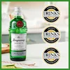 A bottle of Tanqueray London Dry Gin is displayed on a table with lime slices and a bar spoon, accompanied by three circular marketing badges. Produktbild-Vorschau