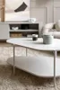 A modern living room scene featuring a coffee table with a teapot and cup, a console table with decorative items, and a piece of abstract art on the wall. Produktbild-Vorschau