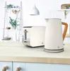 A kitchen counter with a toaster and kettle, with shelves and plants in the background. Voir les images du produit