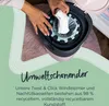 A person's hands are shown inserting a diaper into a diaper pail. The background is a soft rug and the image has a green overlay with text. Produktbild-Vorschau