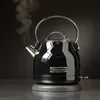 A black KitchenAid electric kettle with steam coming out of the spout, resting on its base. Produktbild-Vorschau