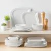 A collection of white porcelain dinnerware is displayed on a shelf against a white background. Náhled obrázku produktu