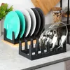 A kitchen counter with two black dish racks, one holding several plates and the other holding pot lids. Náhled obrázku produktu