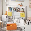 A children's bookshelf filled with toys and books, next to a bed. Anteprima dell’immagine prodotto