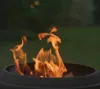 A close-up shot of a LANDMANN fire pit with flames burning inside, set against a blurred green background. Anteprima dell’immagine prodotto