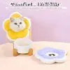 A cat wearing a yellow cone-shaped collar sits on a white stool, with a purple flower-shaped mat in the foreground. Produktbild-Vorschau
