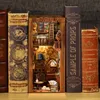 A miniature DIY book nook kit designed to look like a cozy, atmospheric bookstore, placed between several large, decorative books. Voir les images du produit