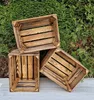 Three wooden crates are arranged in front of a green hedge. Produktbild-Vorschau