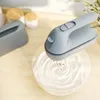 A hand mixer whipping cream in a glass bowl on a wooden countertop. Podgląd zdjęcia produktu