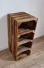 A tall, narrow shelving unit made of wooden crates against a white wall and on a wooden floor. Produktbild-Vorschau