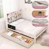 A white children's bed with a bookshelf headboard and storage drawers, shown in a bedroom setting with decorative elements on the wall. Náhľad obrázku produktu