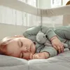A baby sleeping in a crib with a teddy bear. Náhled obrázku produktu