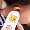 Close-up of a person using an ear thermometer on another person's ear. Produktbild-Vorschau