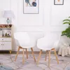 Two white chairs with wooden legs are placed on a patterned rug in a room with white walls and decorative molding. Voir les images du produit