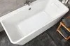 A white bathtub with a white bath mat inside, a faucet, and a bath pillow. The floor is dark gray, and there is a wooden shelf with gray towels next to the tub. Produktbild-Vorschau