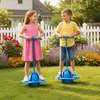 Zwei Kinder, ein Junge und ein Mädchen, spielen aktiv mit blauen Pogo-Springern auf einem grasigen Rasen Podgląd zdjęcia produktu