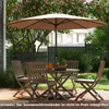 A patio set with a large umbrella and table with chairs, set on a wooden deck in a garden. Produktbild-Vorschau