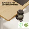 A close-up of a desk with a cup holder attached to the edge, holding a disposable coffee cup. There are also certification logos at the bottom right. Podgląd zdjęcia produktu