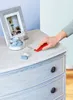 A hand is using a red tool to apply wax to a dresser. Podgląd zdjęcia produktu