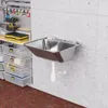 A stainless steel sink mounted on a concrete wall in a workshop or garage setting, with storage bins and tools visible in the background. Produktbild-Vorschau
