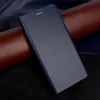 A dark blue flip cover case for a smartphone is shown on a textured background of dark blue, brown, and black materials. Produktbild-Vorschau