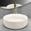 A white ceramic sink with a gold faucet is shown in a bathroom setting. Náhľad obrázku produktu