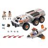 A set of PLAYMOBIL® toys including a large battle truck, a small jet, two figures, and various accessories, laid out on a white background. Produktbild-Vorschau