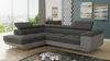 A modern living room with a large sectional sofa, artwork on the wall, and a city view through the window.