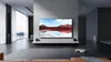A modern living room with a large TV displaying a landscape image, a robot vacuum cleaner on the floor, and large windows. Voir les images du produit