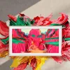 A TV screen displaying a colorful painting is surrounded by splashes of paint. Produktbild-Vorschau