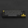 A mechanical keyboard with black, gray, and yellow keys is shown from a top-down perspective on a black textured surface. Produktbild-Vorschau