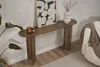 A wooden console table with decor items and a framed picture on it, placed against a white wall next to a sofa. Voir les images du produit