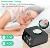A person sleeping in bed next to a digital alarm clock. Produktbild-Vorschau